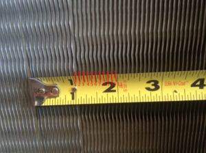 Tape measure held against coil fins to count fins per inch
